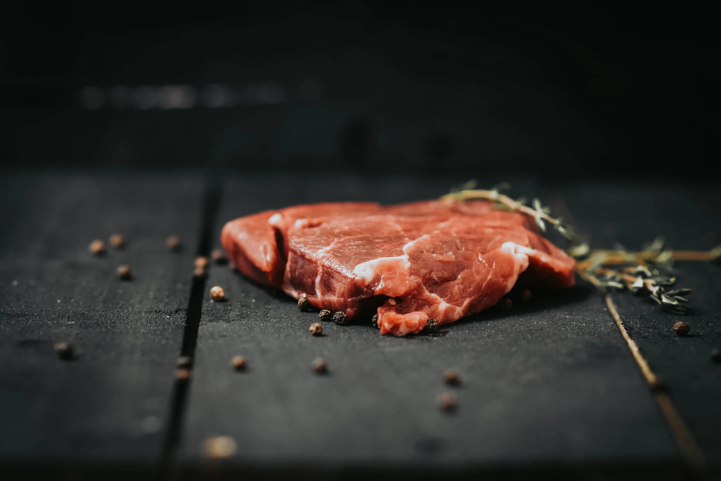 Beef tenderloin steak from Pure Valley Farms on slate with peppercorns and thyme